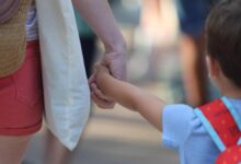 Un niño camina de la mano de su madre hacia su colegio.