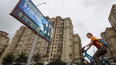 Una mujer pasa en bici junto a un cartel que llama al reclutamiento para el ejército, este martes en Moscú.