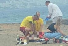 Los equipos de rescate atienden a la mujer en la orilla de la playa.