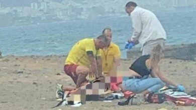 Los equipos de rescate atienden a la mujer en la orilla de la playa.