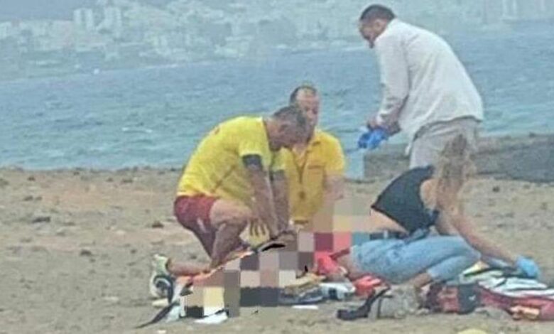 Los equipos de rescate atienden a la mujer en la orilla de la playa.