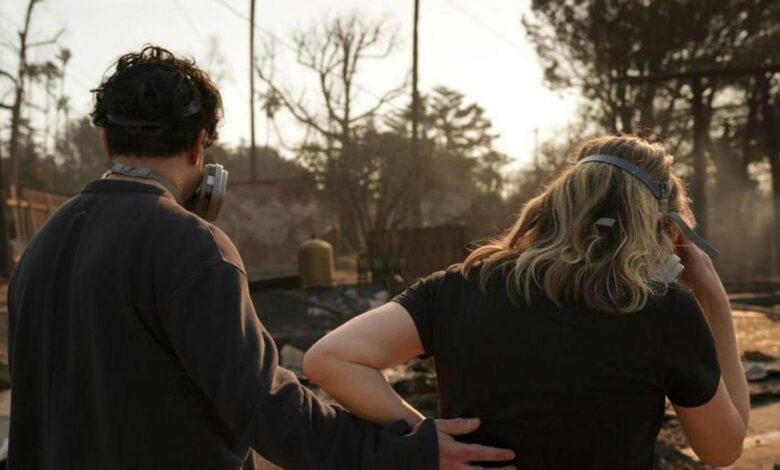 Una pareja observa el paisaje desolado tras el incendio.